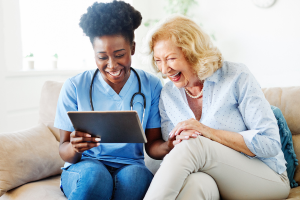 a senior woman looking at a tablet, smiling with her doctor