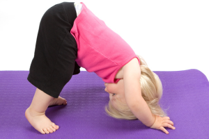 Child in yoga pose on purple mat