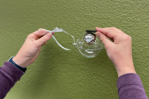 Jingle bell inside a clear tree ornament being pulled up by a magnet