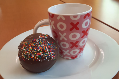 Ball of chocolate with sprinkles next to hot cocoa mug.