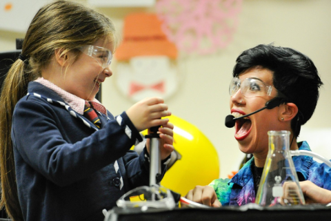 Child with safety goggles holding a beaker