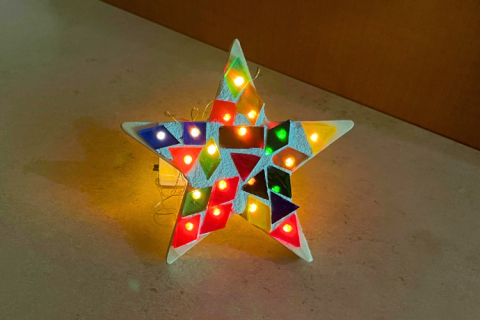 Tiny lights shine through multi-colored tiles on a star cutout