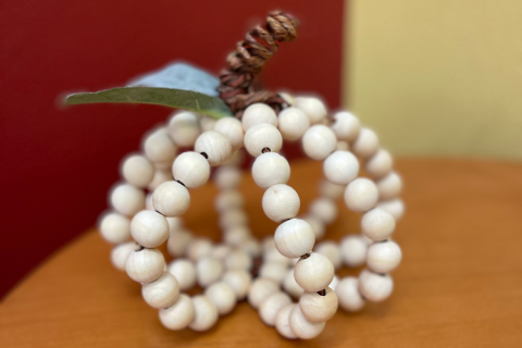 A pumpkin created from wire and chunky wooden beads.