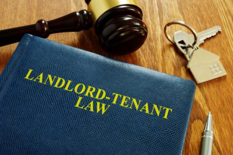 A book of Landlord-Tenant Law next to a gavel and a house key.