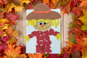 scarecrow made from torn paper surrounded by fall leaves