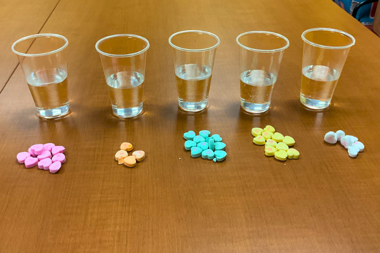 A row of colorful Valentine candy in front of small glasses of water