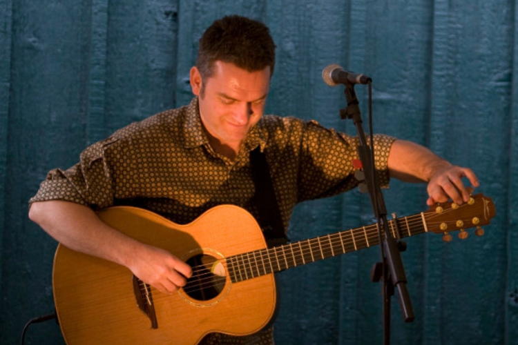 Musician Ian Gould tuning an acoustic guitar