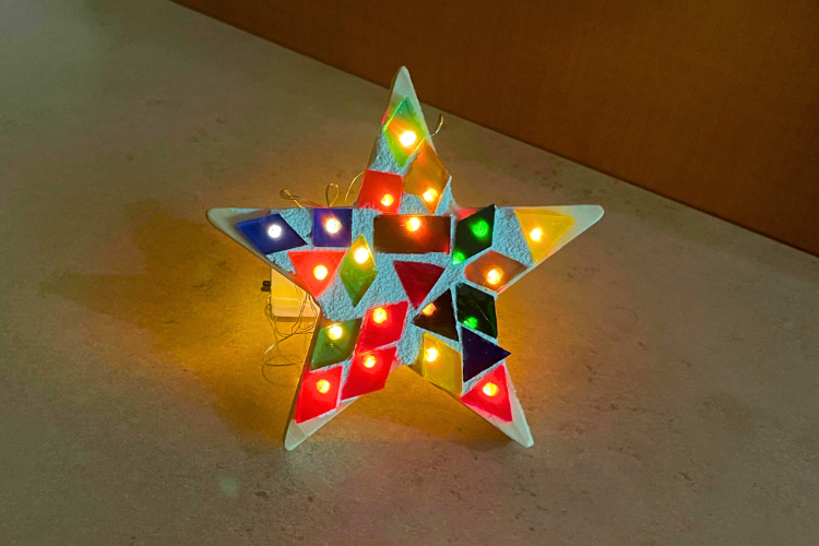 Tiny lights shine through multi-colored tiles on a star cutout