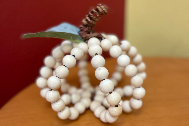 A pumpkin created from wire and chunky wooden beads.